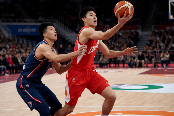 篮球比赛现场球员突破上篮，防守球员紧跟其后